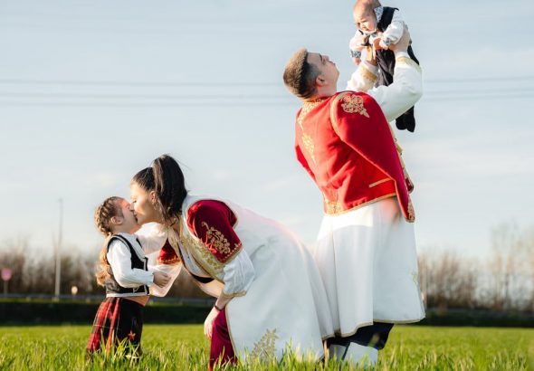 Joyful family in traditional attire playing in a sunny field, embracing cultural heritage.