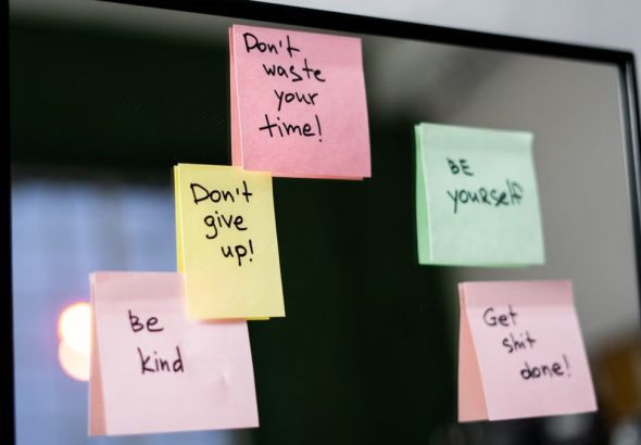 Colorful sticky notes with motivational messages on a mirror reflecting positivity.